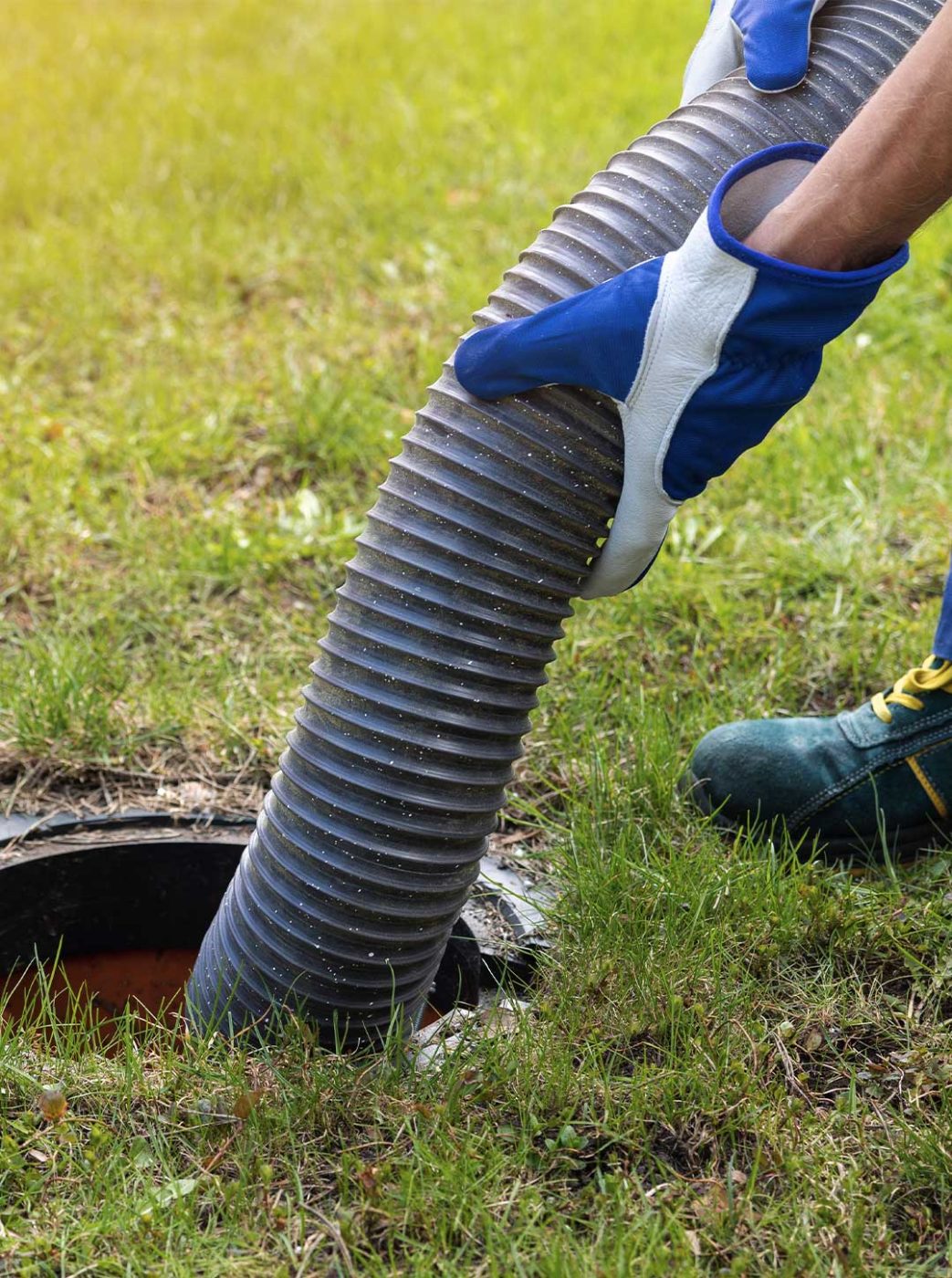 Worker putting pumping tube in a septic tank.